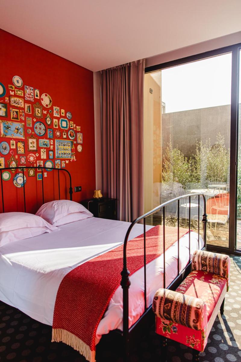 um quarto com uma cama com uma parede vermelha em Cooking and Nature - Emotional Hotel em Alvados
