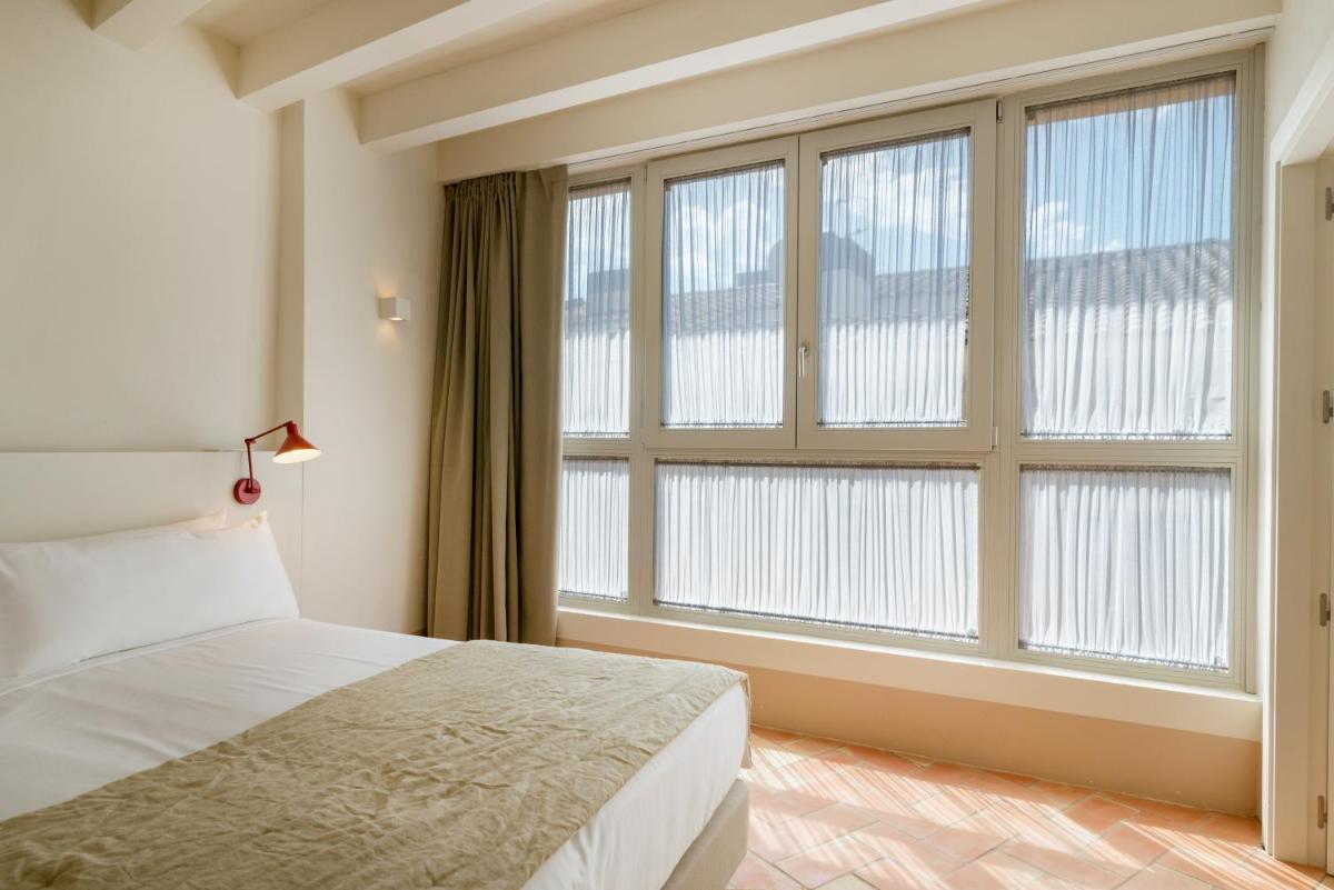 Un dormitorio con una cama y una ventana grande. en Can Mascort Eco Hotel, en Palafrugell