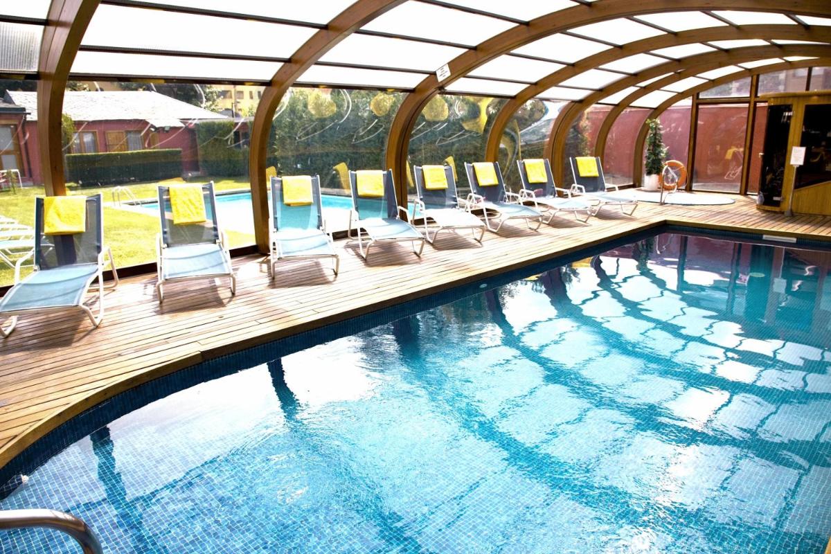 una piscina con sillas y una piscina en Hotel Del Lago, en Puigcerdà