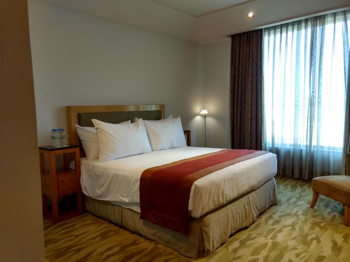 a hotel room with a bed and a window at The Grand New Delhi in New Delhi a hotel room with a bed and a window at The Grand New Delhi in New Delhi