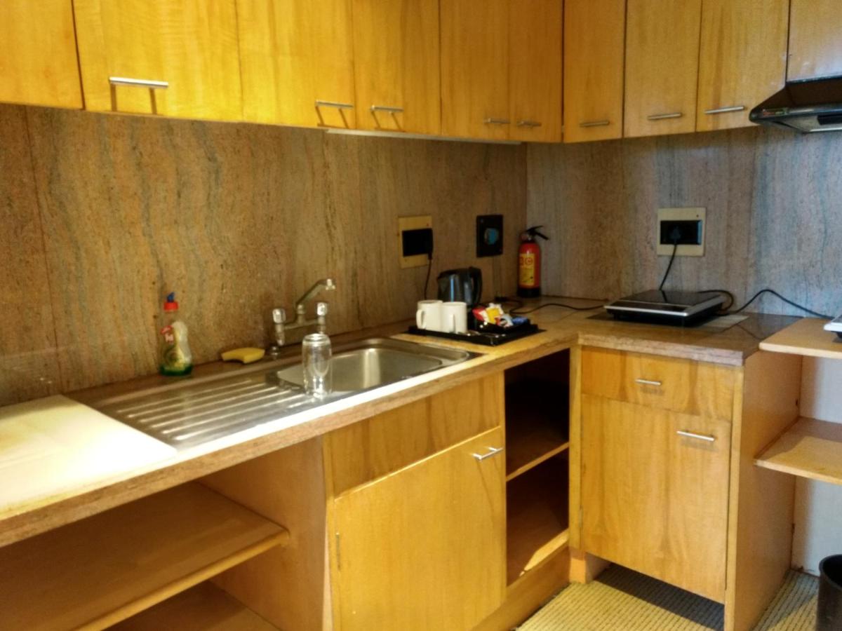 a kitchen with wooden cabinets and a sink at The Grand New Delhi in New Delhi a kitchen with wooden cabinets and a sink at The Grand New Delhi in New Delhi