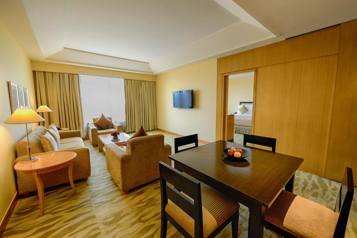 a hotel room with a dining table and a living room at The Grand New Delhi in New Delhi a hotel room with a dining table and a living room at The Grand New Delhi in New Delhi