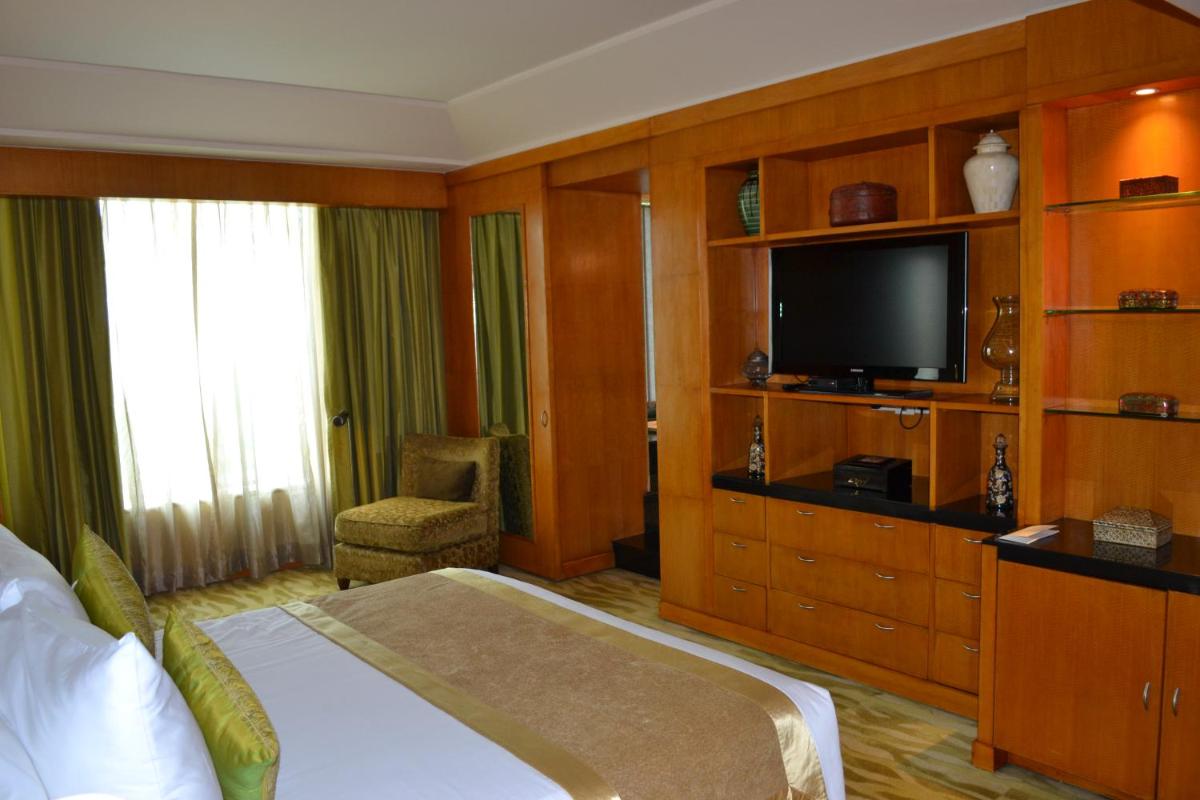 a hotel room with a bed and a flat screen tv at The Grand New Delhi in New Delhi a hotel room with a bed and a flat screen tv at The Grand New Delhi in New Delhi