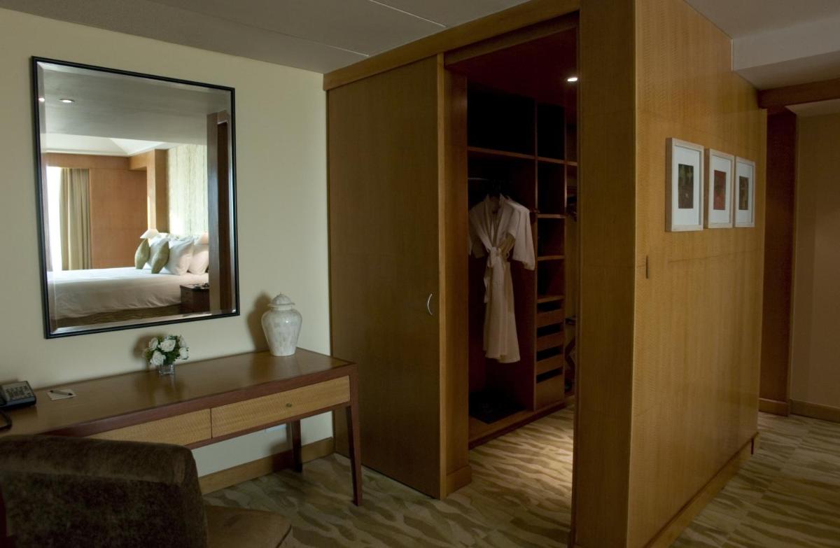 a hotel room with a mirror and a bedroom at The Grand New Delhi in New Delhi a hotel room with a mirror and a bedroom at The Grand New Delhi in New Delhi