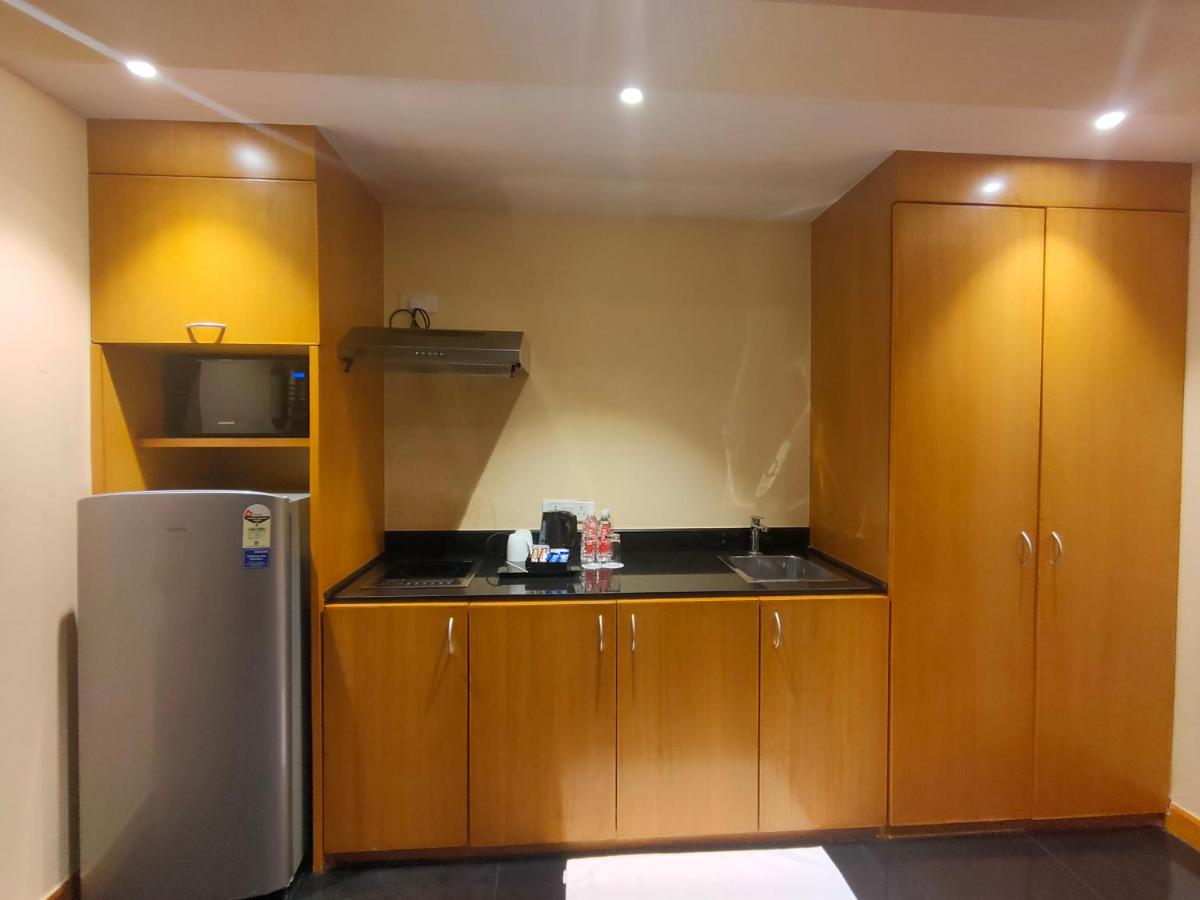 a kitchen with wooden cabinets and a refrigerator at The Grand New Delhi in New Delhi a kitchen with wooden cabinets and a refrigerator at The Grand New Delhi in New Delhi