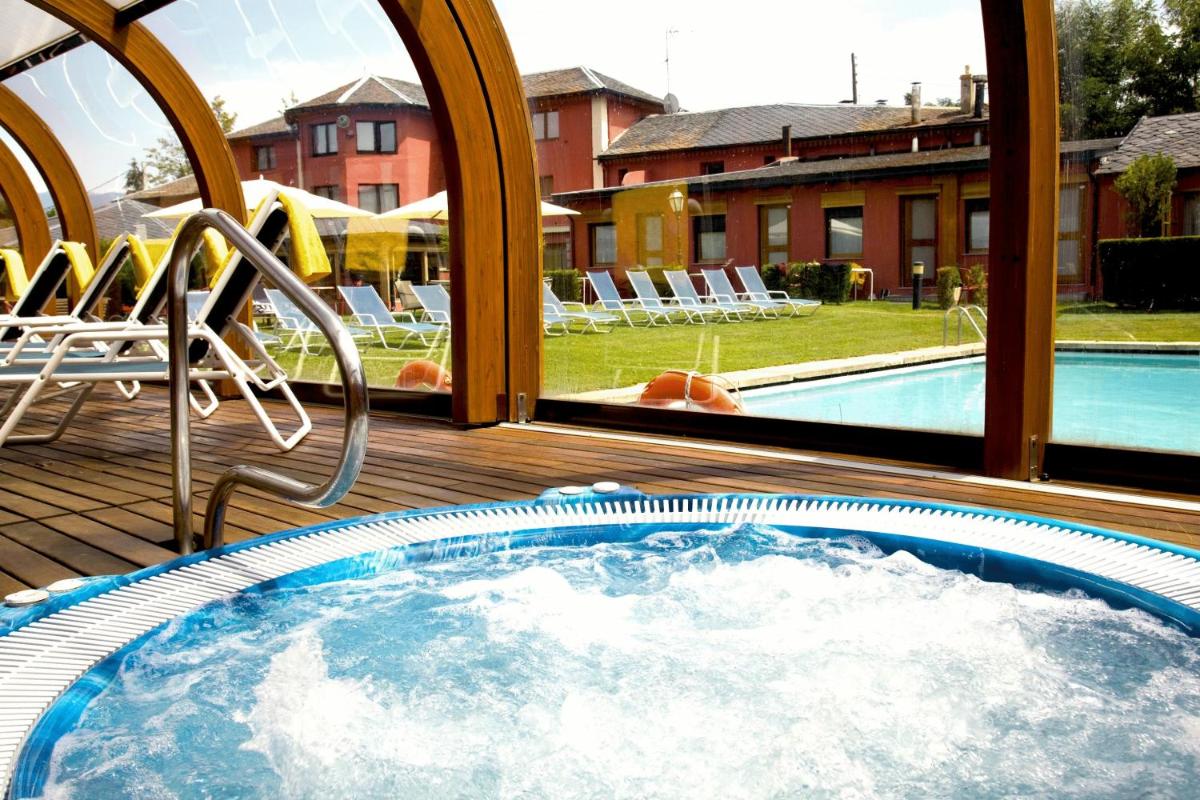 bañera de hidromasaje en una terraza junto a la piscina en Hotel Del Lago, en Puigcerdà