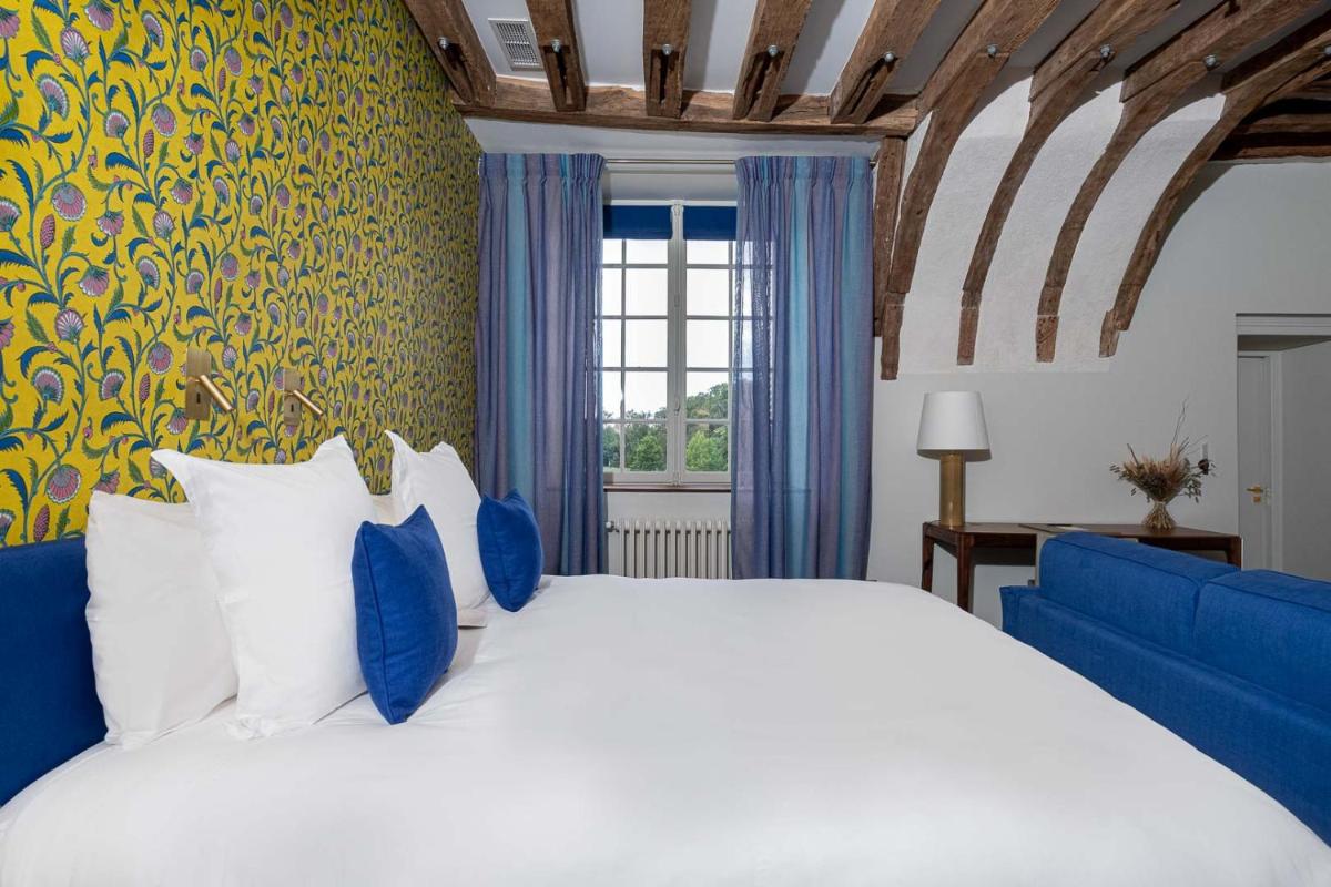 une chambre avec un grand lit et un canapé bleu dans l'établissement La Borde en Sologne Château & Spa, à Vernou-en-Sologne