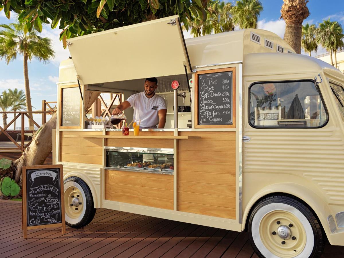 un hombre está preparando comida en un camión de comida en H10 Conquistador, en Playa de las Américas