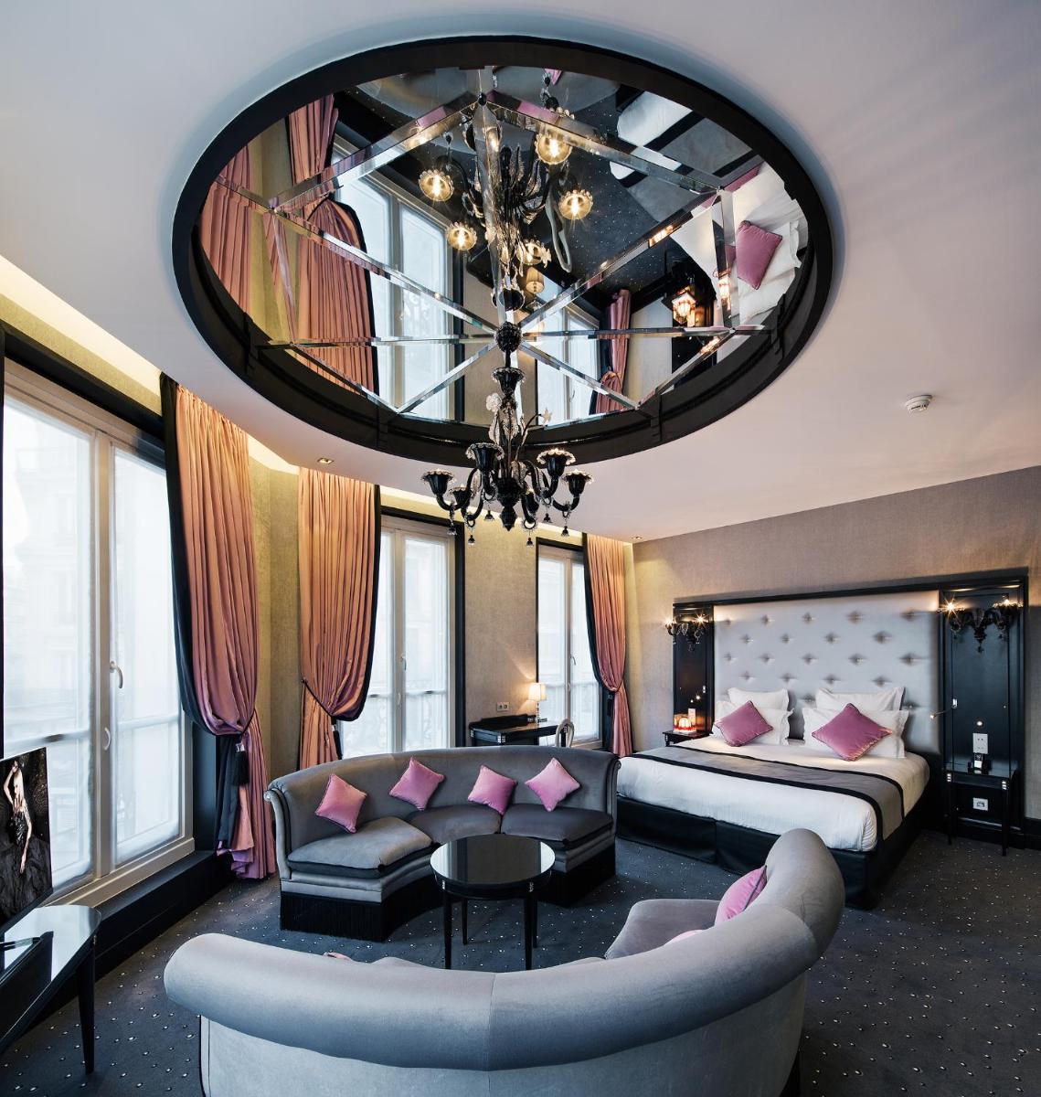 Cette grande chambre comprend un lit et un grand miroir. dans l'établissement Maison Albar - Le Diamond, à Paris