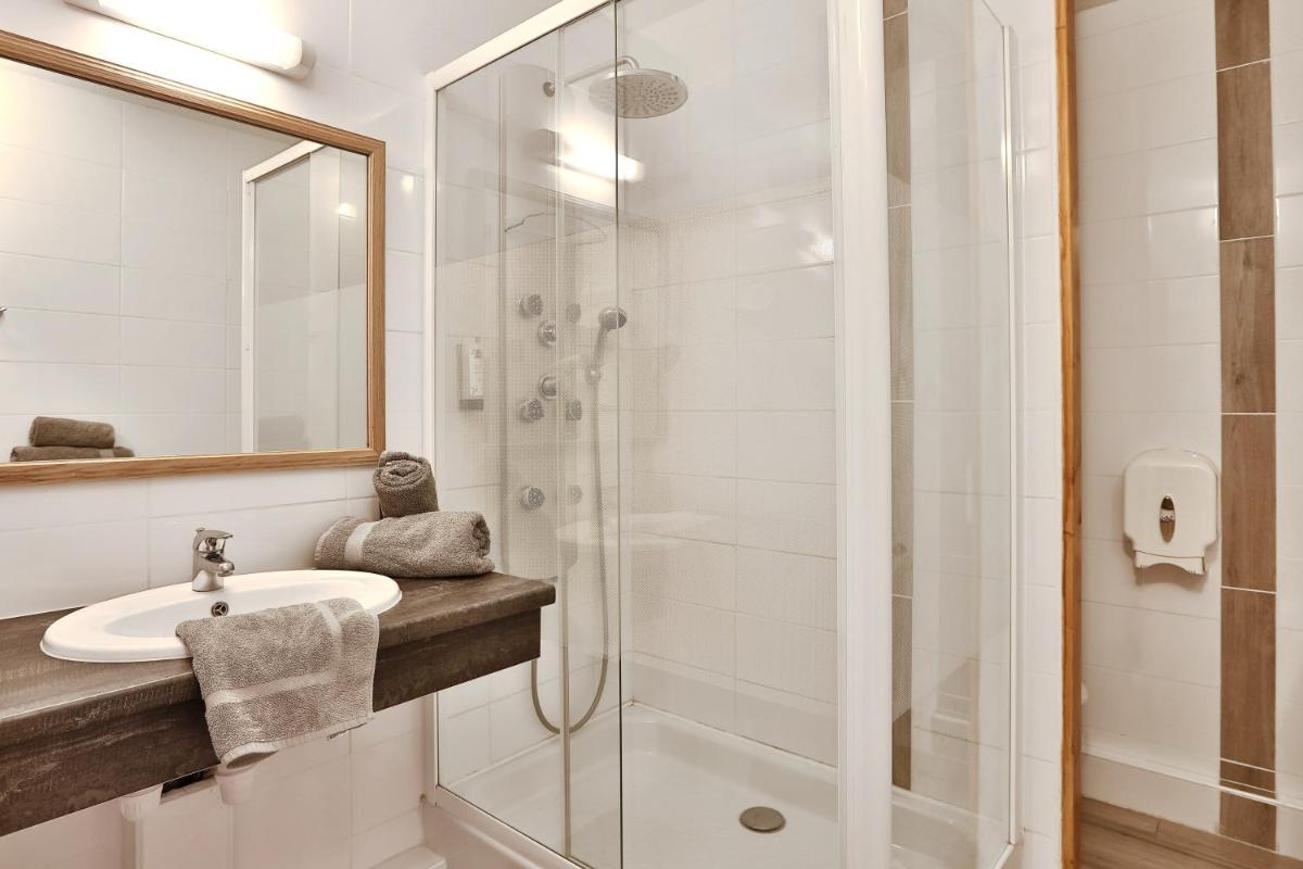 une salle de bain avec lavabo et douche dans l'établissement Logis Hotel Le Tropicana, à Douville
