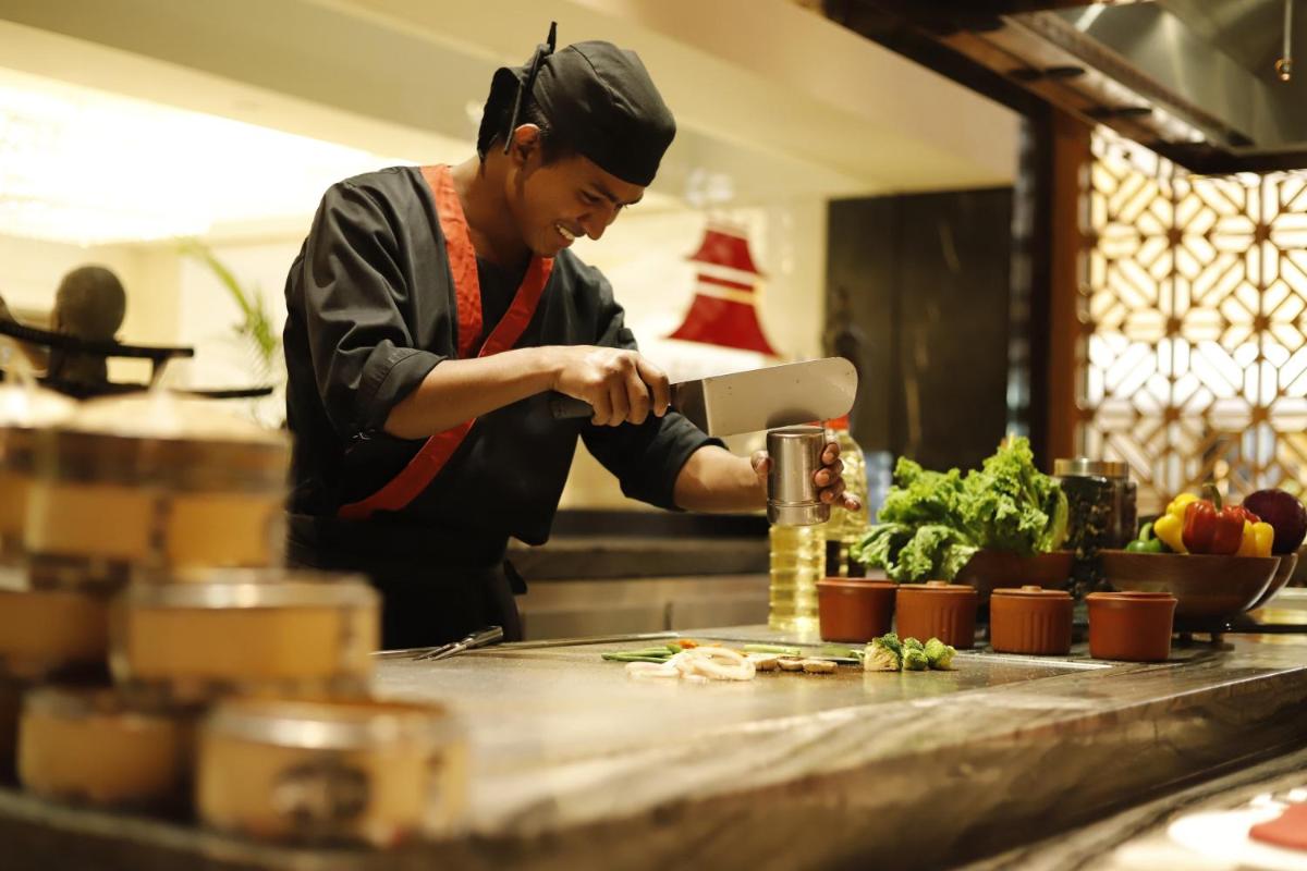a chef preparing food on a counter in a kitchen at InterContinental Jaipur Tonk Road by IHG in Jaipur