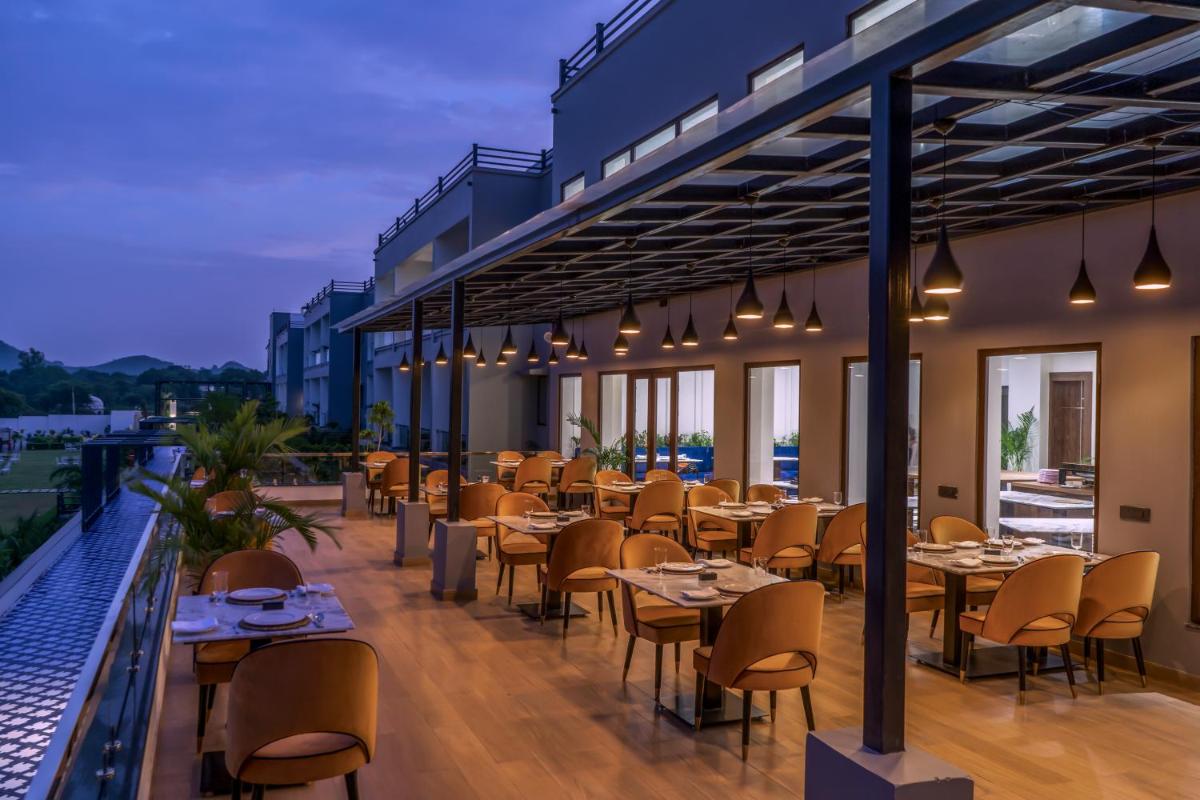 a restaurant with tables and chairs on a balcony at ZANA Lakeview Resort - most scenic lakeside resort in Udaipur