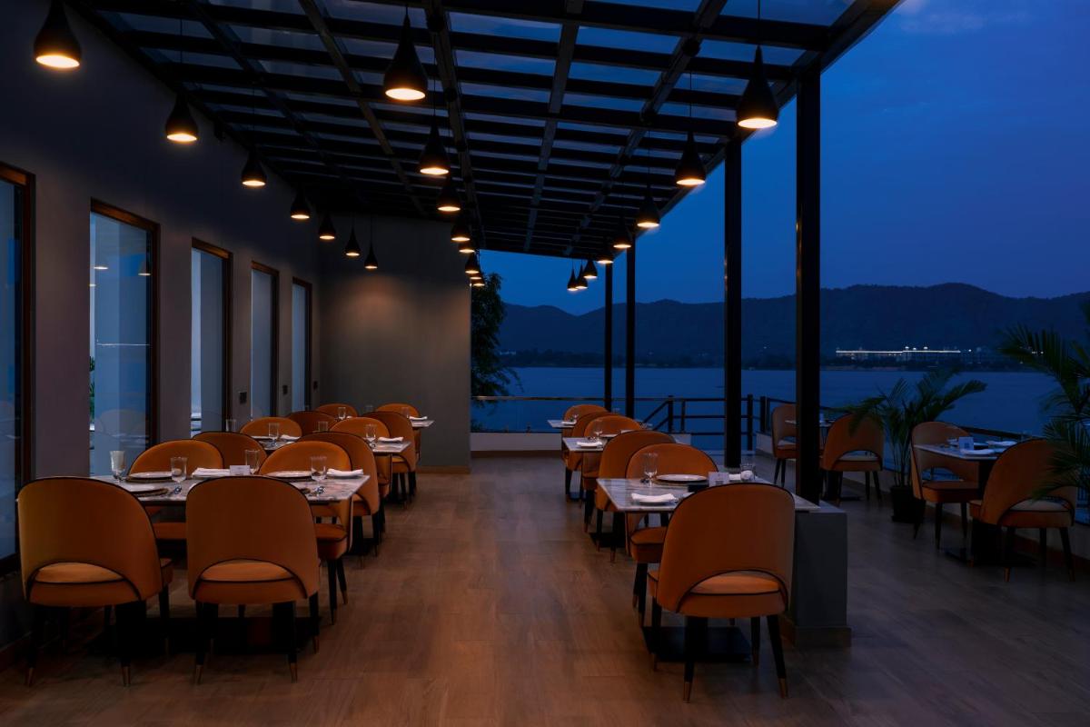 a dining room with tables and chairs with a view at ZANA Lakeview Resort - most scenic lakeside resort in Udaipur