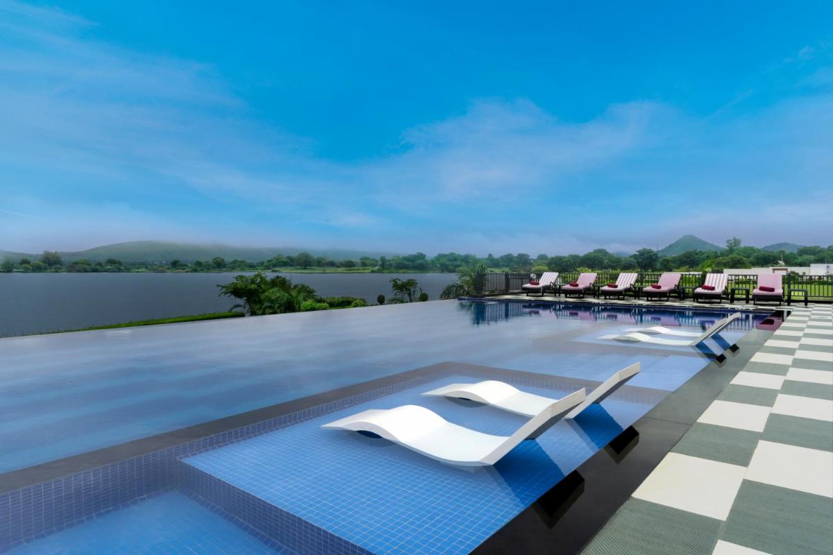 a swimming pool with lounge chairs on the roof of a resort at ZANA Lakeview Resort - most scenic lakeside resort in Udaipur