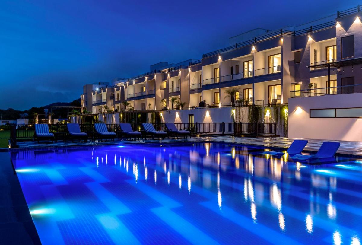 a swimming pool in front of a building at night at ZANA Lakeview Resort - most scenic lakeside resort in Udaipur