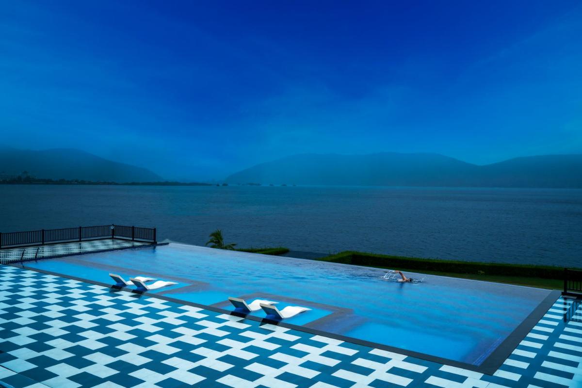 a swimming pool with a view of the water at ZANA Lakeview Resort - most scenic lakeside resort in Udaipur
