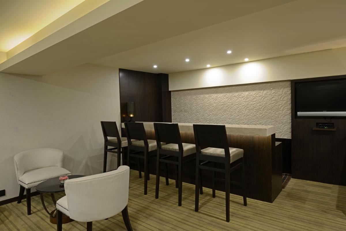 a room with a bar with chairs and a flat screen tv at Sun-n-Sand Mumbai Juhu Beach in Mumbai