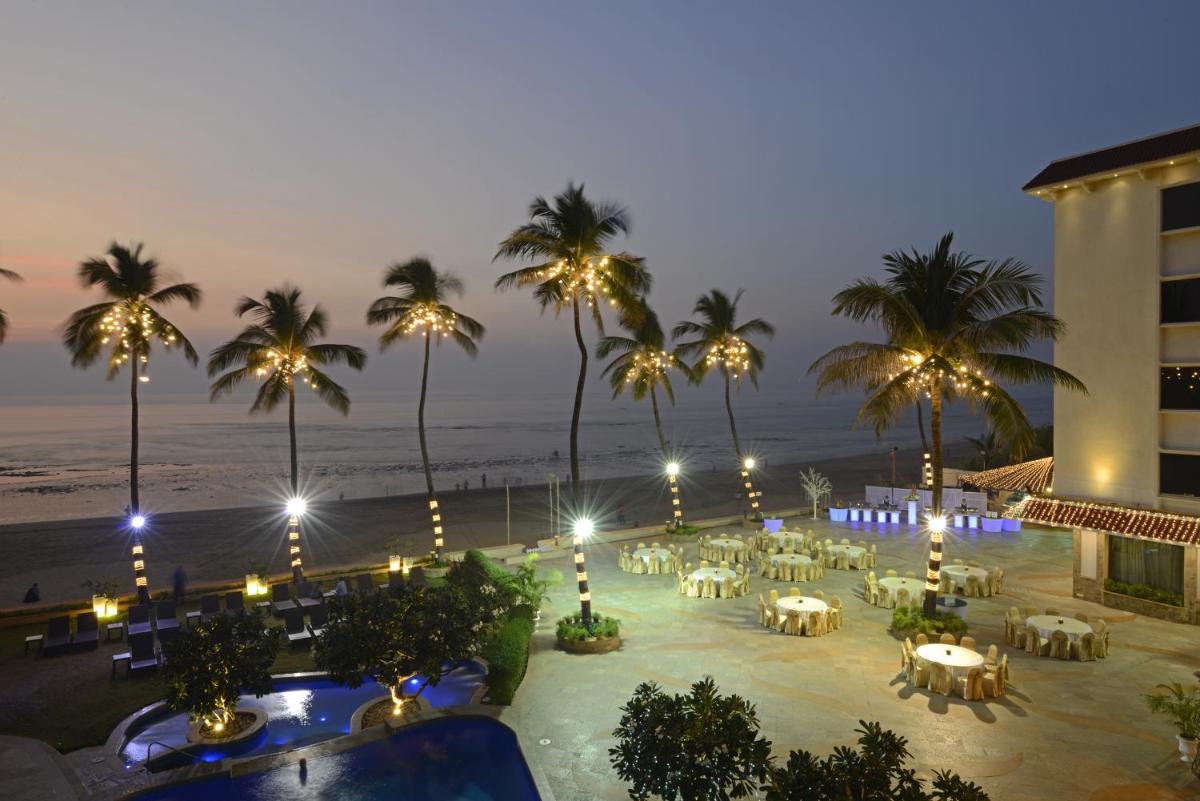 a resort with tables and chairs on the beach at night at Sun-n-Sand Mumbai Juhu Beach in Mumbai