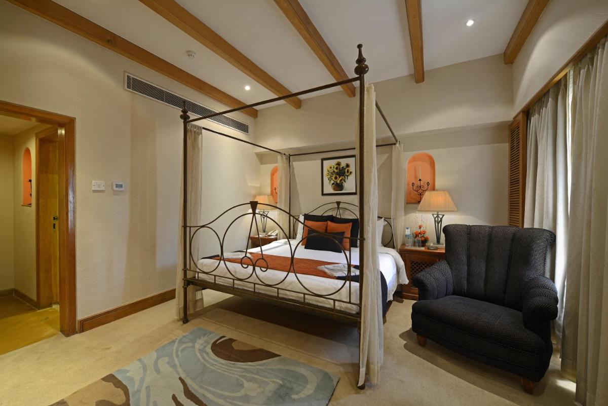 a bedroom with a canopy bed and a chair at Sun-n-Sand Mumbai Juhu Beach in Mumbai