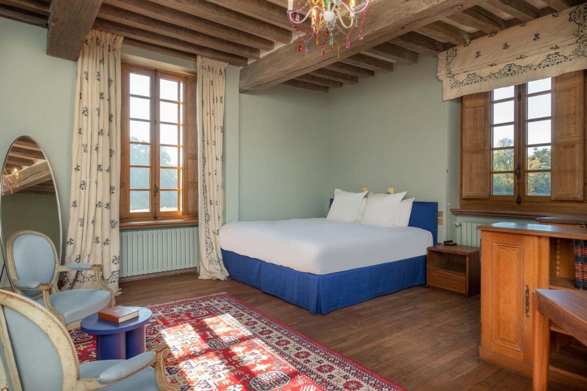 une chambre avec un lit, un bureau et des fenêtres dans l'établissement La Borde en Sologne Château & Spa, à Vernou-en-Sologne