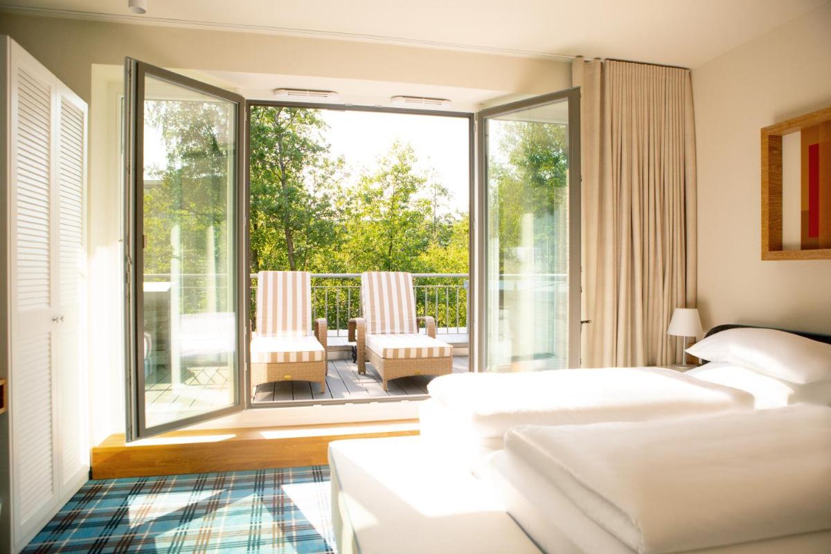 ein Wohnzimmer mit einem Bett und einem großen Fenster in der Unterkunft Aalernhüs hotel & spa in Sankt Peter-Ording