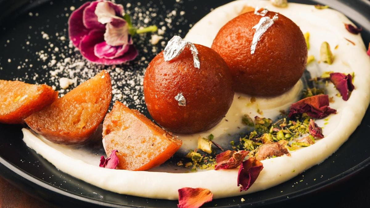 a dessert on a black plate with fruit on it at InterContinental Marine Drive Mumbai by IHG in Mumbai