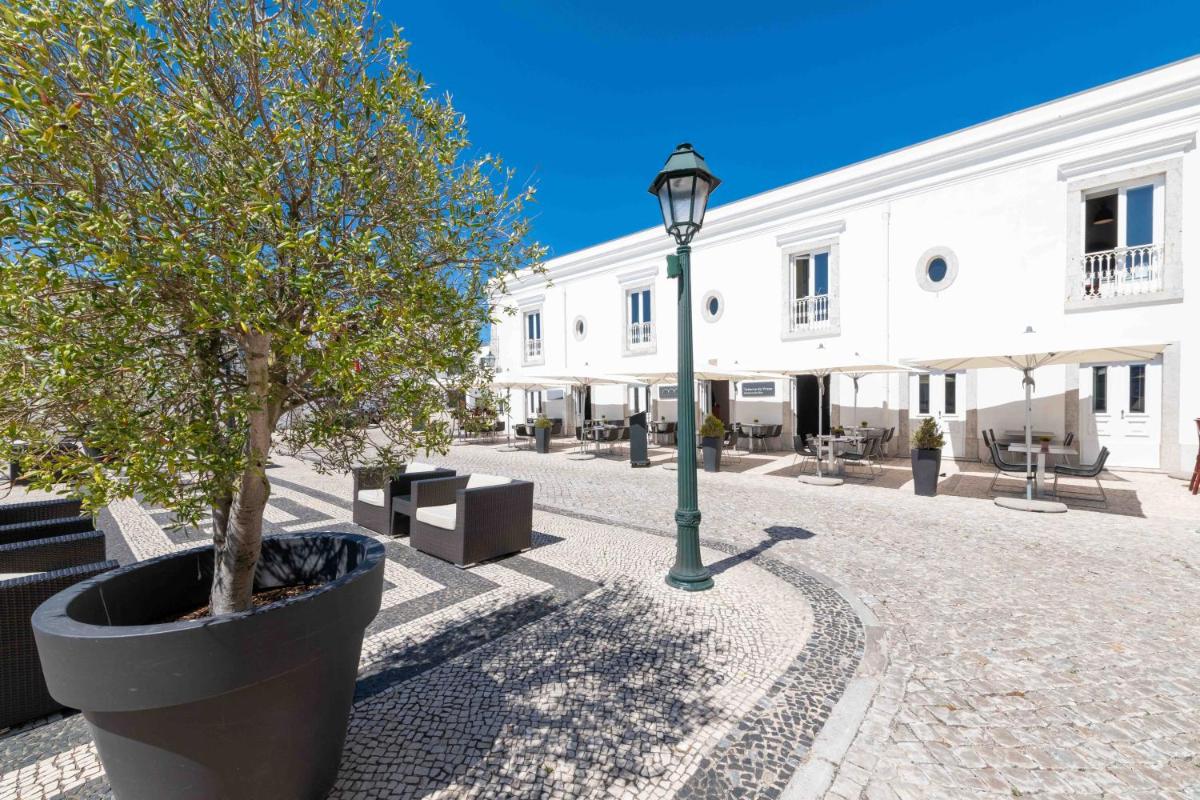 um poste de luz ao lado de um prédio branco com árvores em Pestana Cidadela Cascais - Pousada & Art District em Cascais