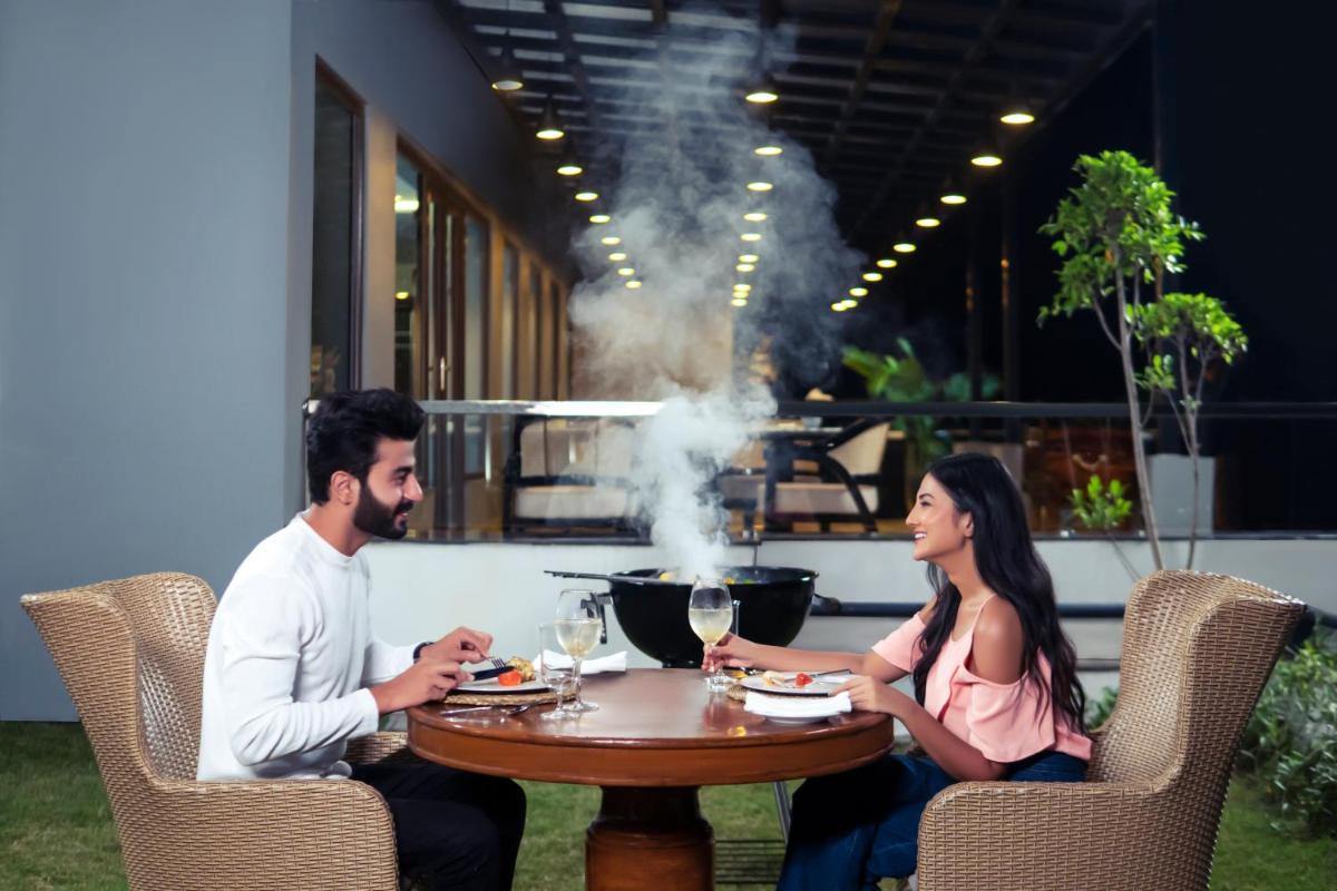 a man and woman sitting at a table with smoke at ZANA Lakeview Resort - most scenic lakeside resort in Udaipur