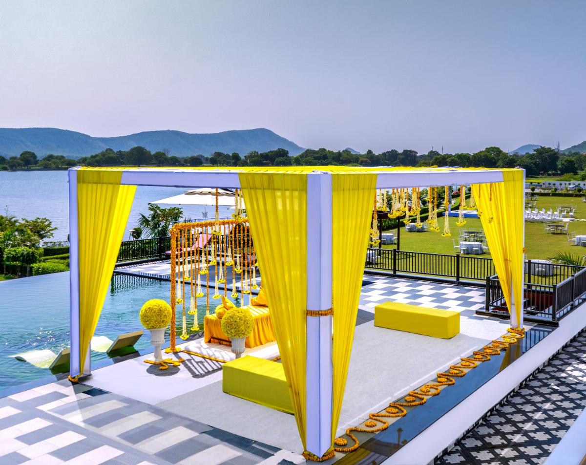 a gazebo with yellow curtains next to a pool at ZANA Lakeview Resort - most scenic lakeside resort in Udaipur