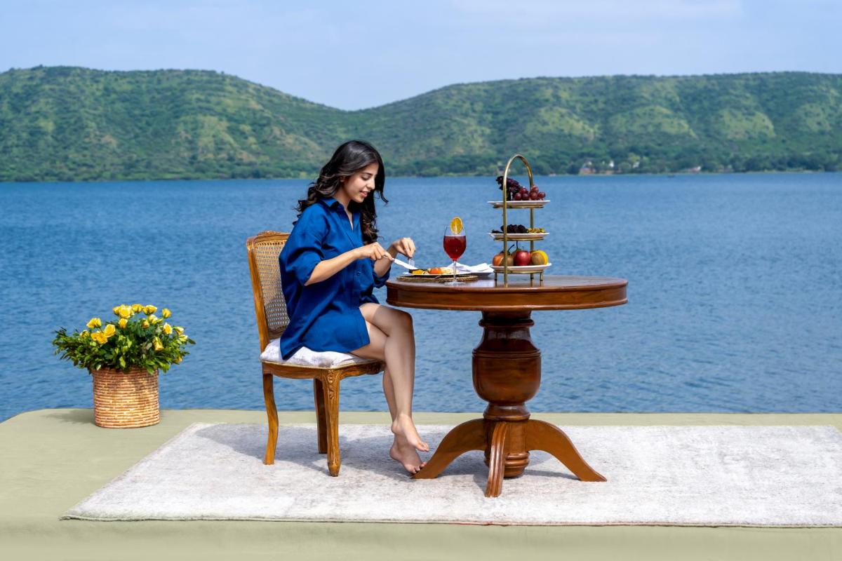 a woman in a blue dress sitting at a table at ZANA Lakeview Resort - most scenic lakeside resort in Udaipur