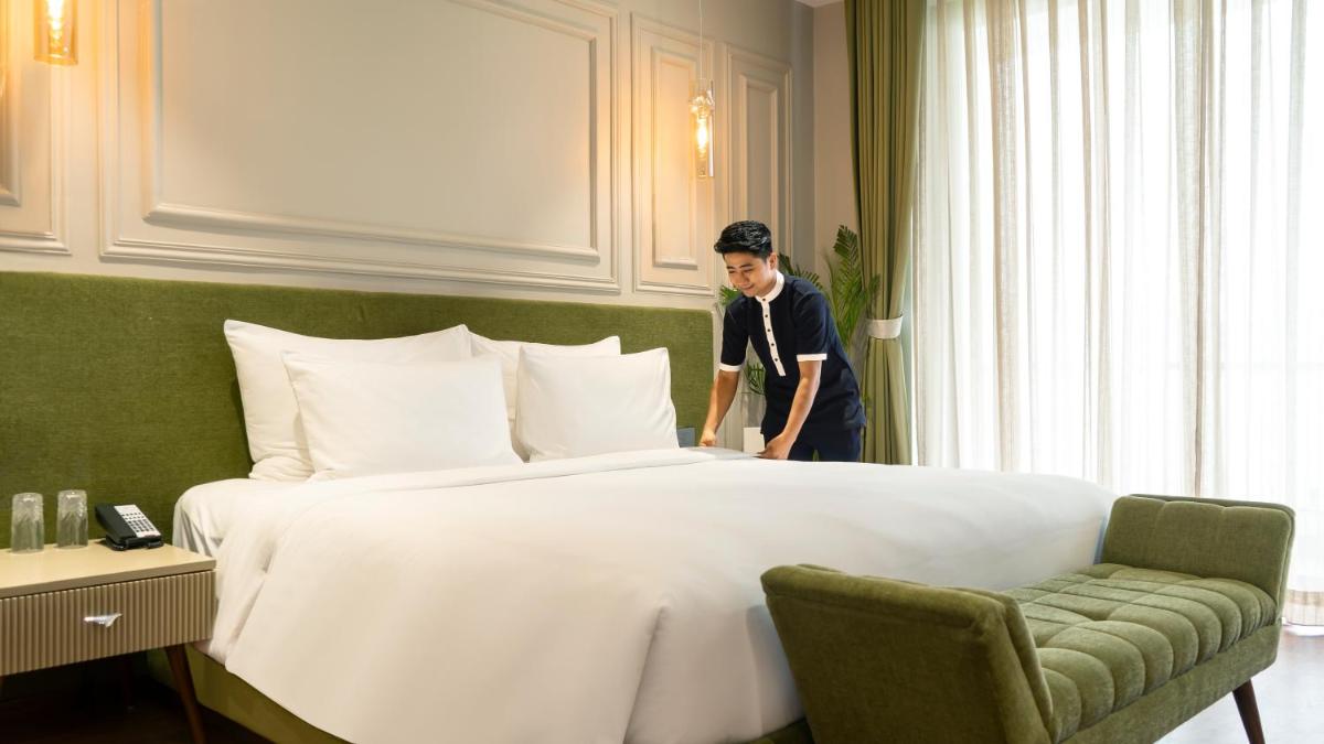a man standing next to a large bed in a hotel room at ZANA Lakeview Resort - most scenic lakeside resort in Udaipur