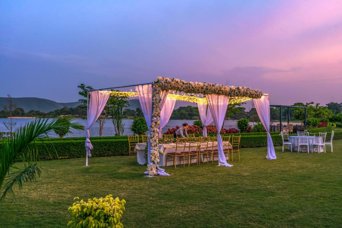 an outdoor wedding with a table set up in the grass at ZANA Lakeview Resort - most scenic lakeside resort in Udaipur +72 photos