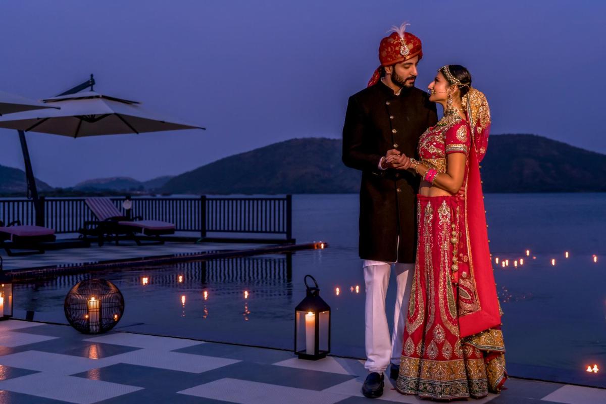 a bride and groom standing next to a pool at ZANA Lakeview Resort - most scenic lakeside resort in Udaipur