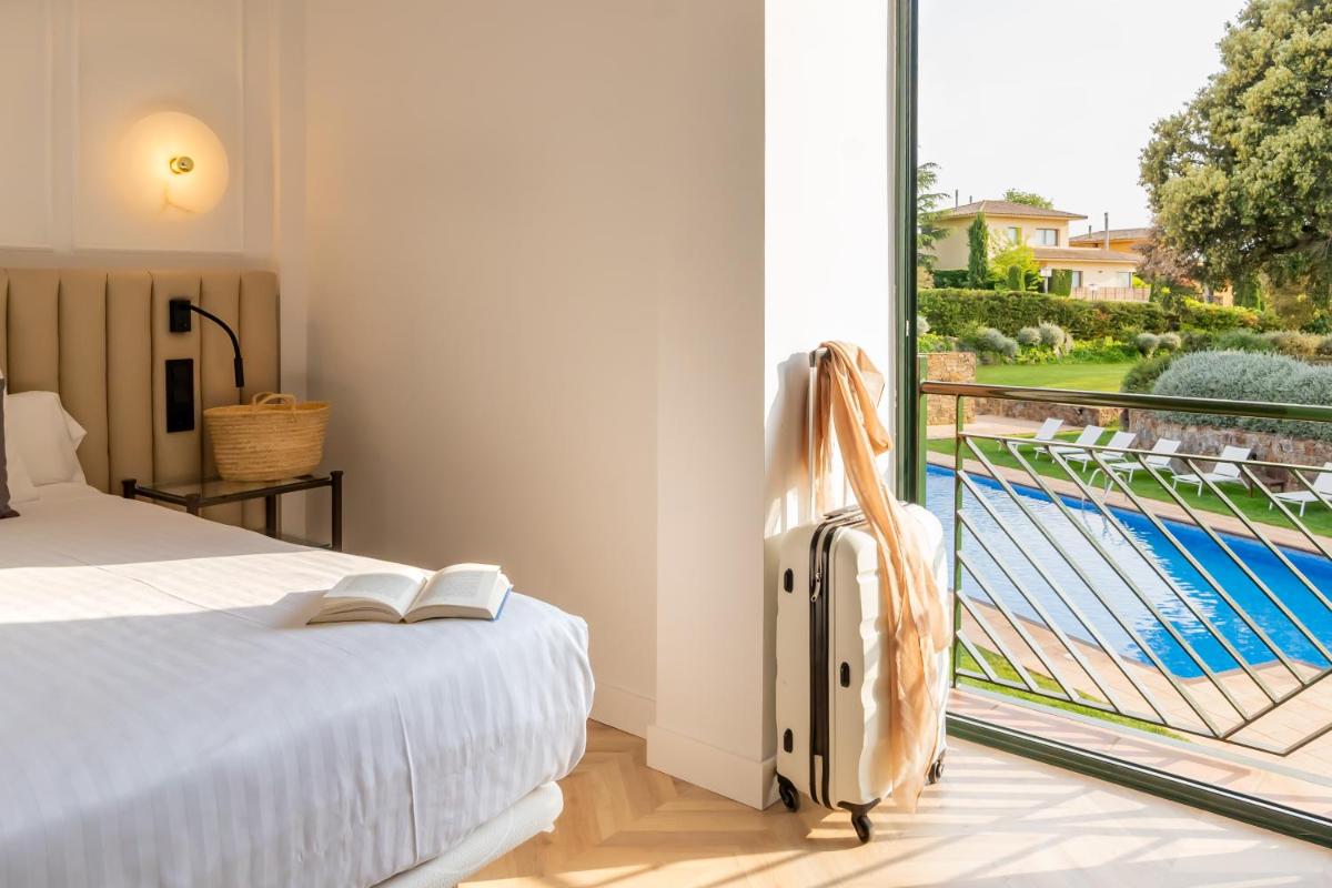 Un dormitorio con una cama y vistas a una piscina. en Hotel TorreMirona Golf & Spa, en Navata