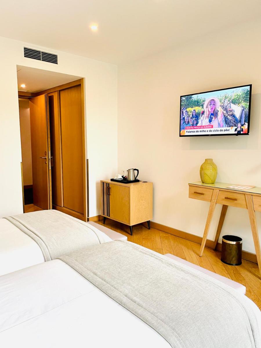 um quarto com duas camas e uma tv na parede em Castelo Hotel em Chaves