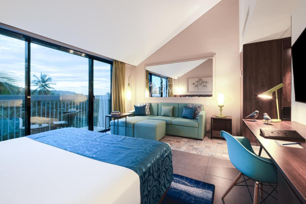 a hotel room with a bed and a desk and a couch at Hyatt Centric Candolim Goa in Calangute a hotel room with a bed and a desk and a couch at Hyatt Centric Candolim Goa in Calangute
