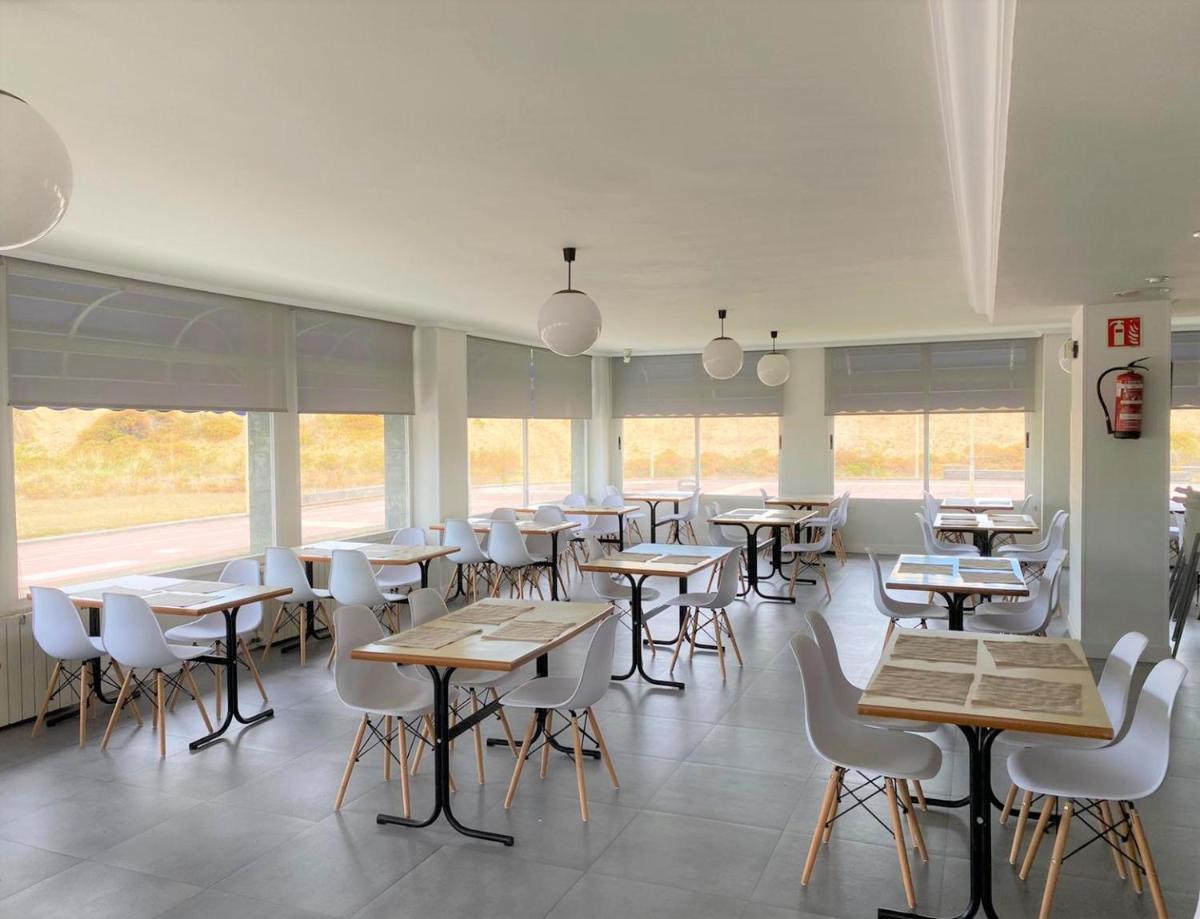 Un comedor con mesas y sillas y ventanas. en Hotel Playamar Spa, en Laredo