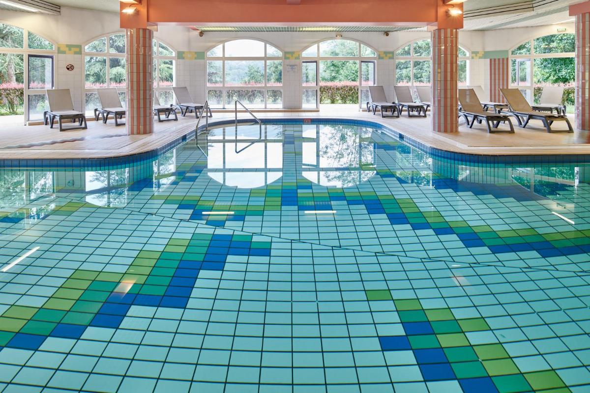 une piscine avec un sol carrelé coloré dans un hôtel dans l'établissement Hotel *** & Spa Vacances Bleues Villa Marlioz, à Aix-les-Bains