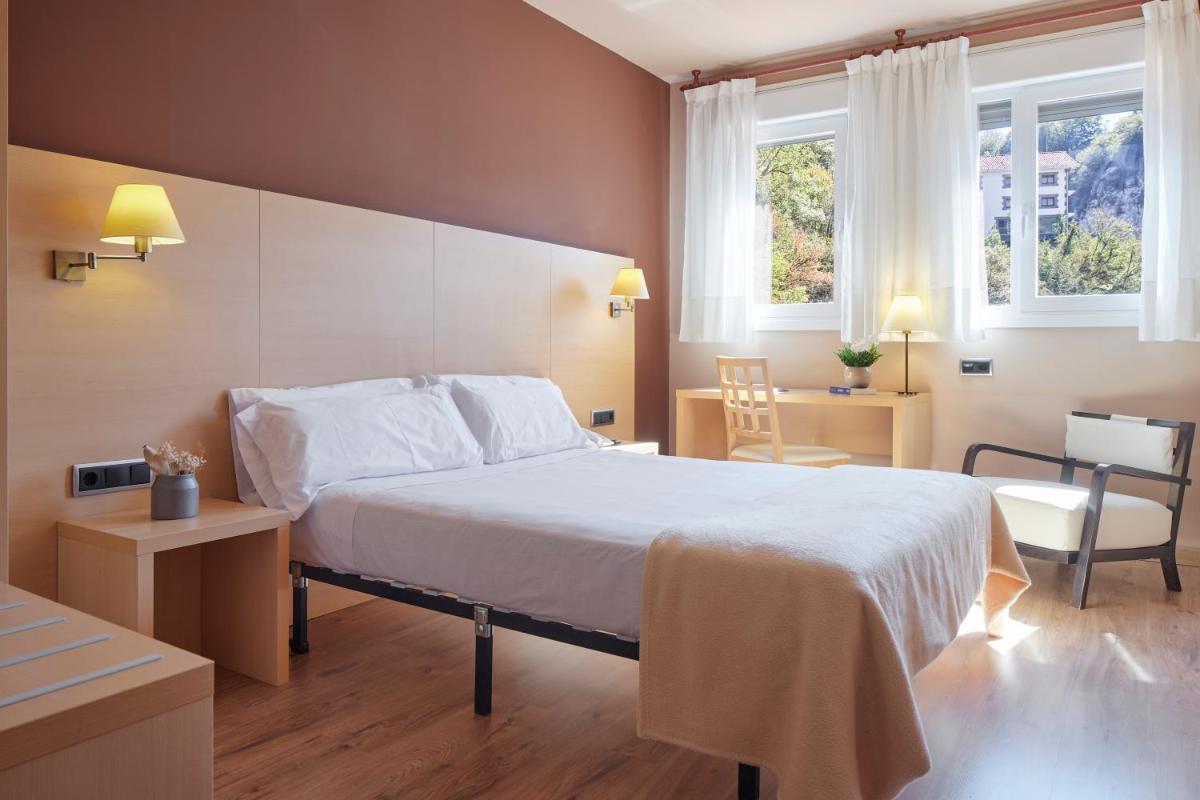 Una habitación de hotel con una cama, una mesa y sillas. en Iraipe Santuario de Arantzazu Hotel, en Oñate 79 fotos más