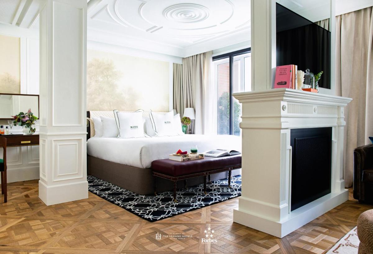 Un dormitorio con una cama y una chimenea. en BLESS Hotel Madrid - The Leading Hotels of the World, en Madrid