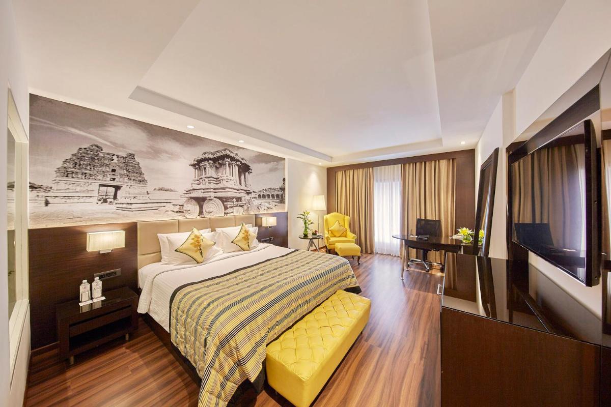 a hotel room with a bed and a tv at Hotel Royal Orchid Bangalore in Bengaluru