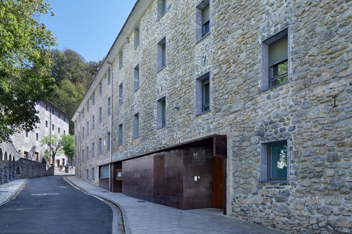 Un gran edificio de piedra con garaje en una calle. en Iraipe Santuario de Arantzazu Hotel, en Oñate