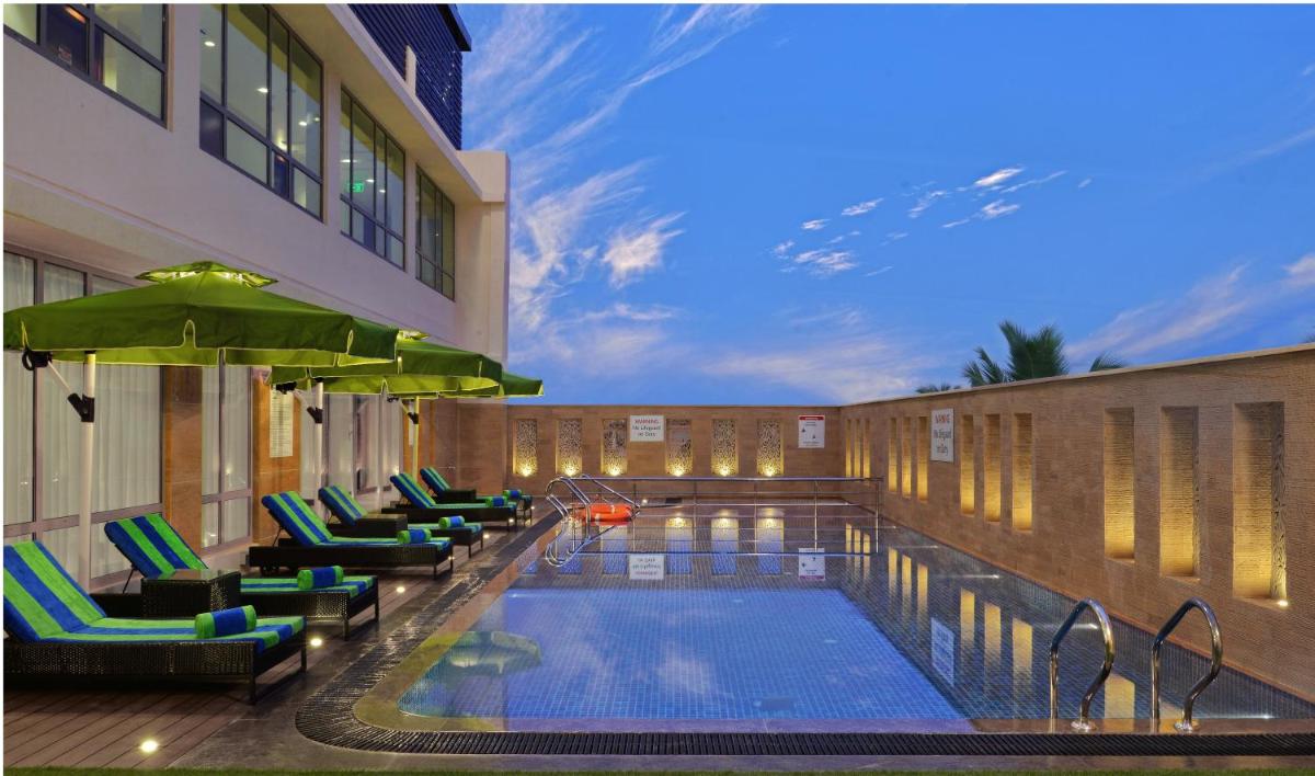 a hotel swimming pool with chairs and a building at Fortune Miramar, Goa - Member ITC Hotels' Group in Panaji a hotel swimming pool with chairs and a building at Fortune Miramar, Goa - Member ITC Hotels' Group in Panaji