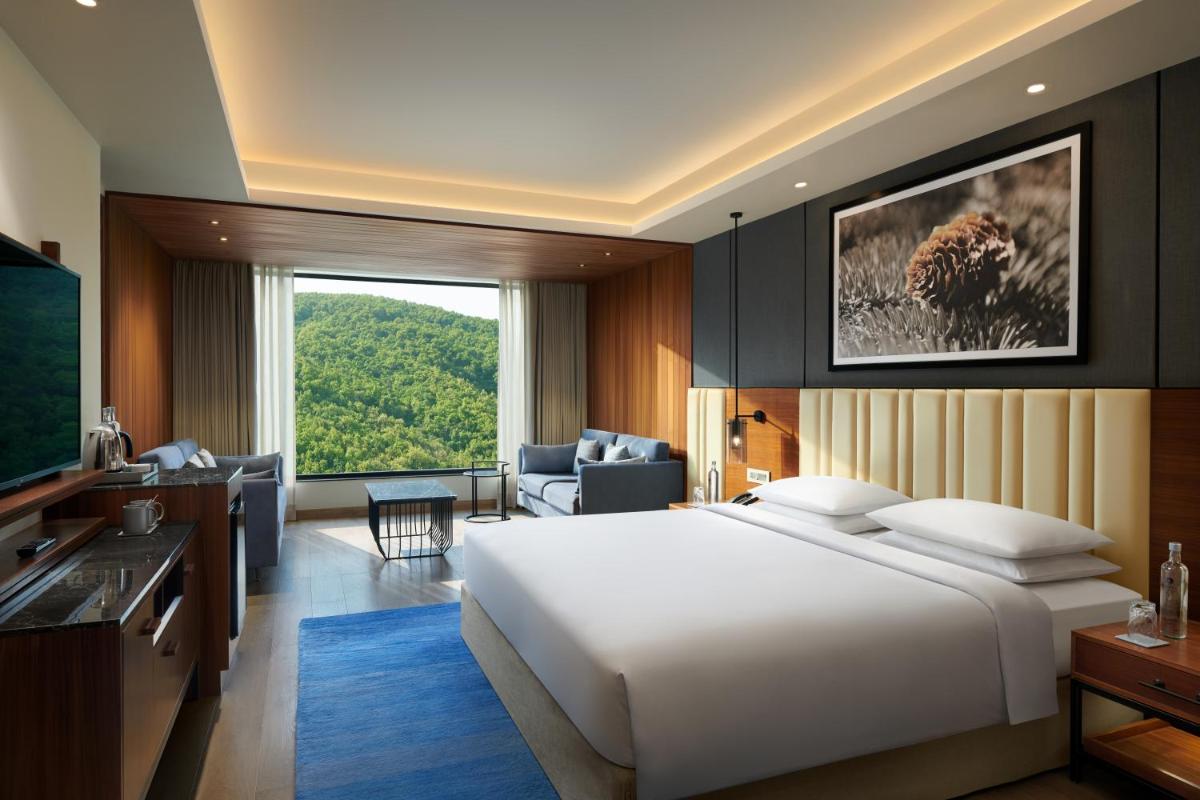 a bedroom with a large white bed and a living room at Hyatt Regency Dehradun Resort and Spa in Dehradun