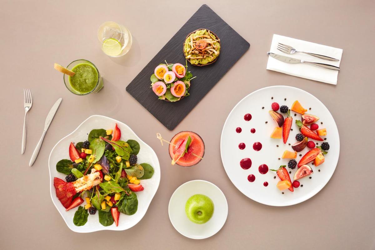 uma mesa com dois pratos brancos de alimentos em Longevity Health & Wellness Hotel - Adults Only em Alvor