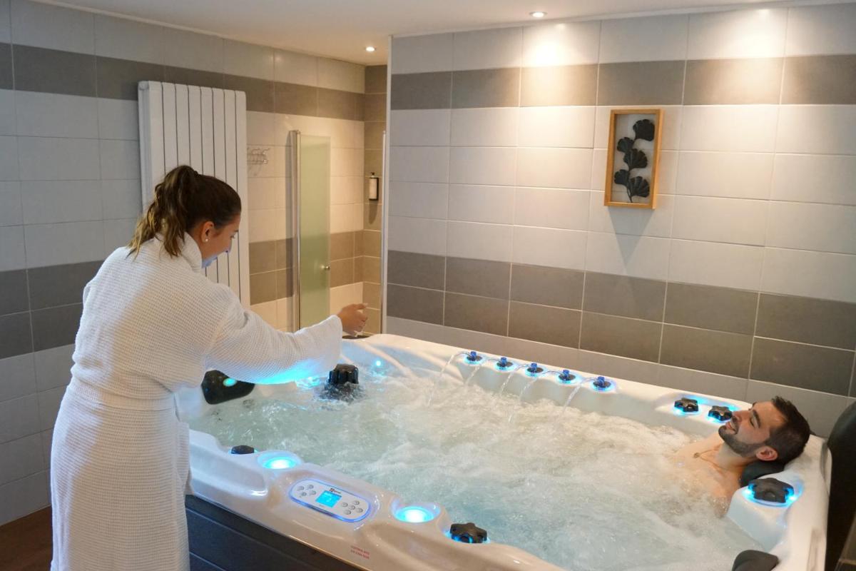 une femme et un homme dans une baignoire dans l'établissement Logis hôtel Aux Berges de l'Aveyron, à Onet le Château