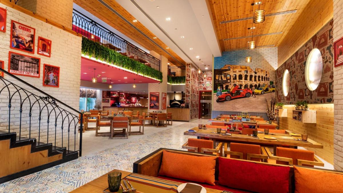 a restaurant with orange chairs and tables in a restaurant at Holiday Inn New Delhi Aerocity by IHG in New Delhi