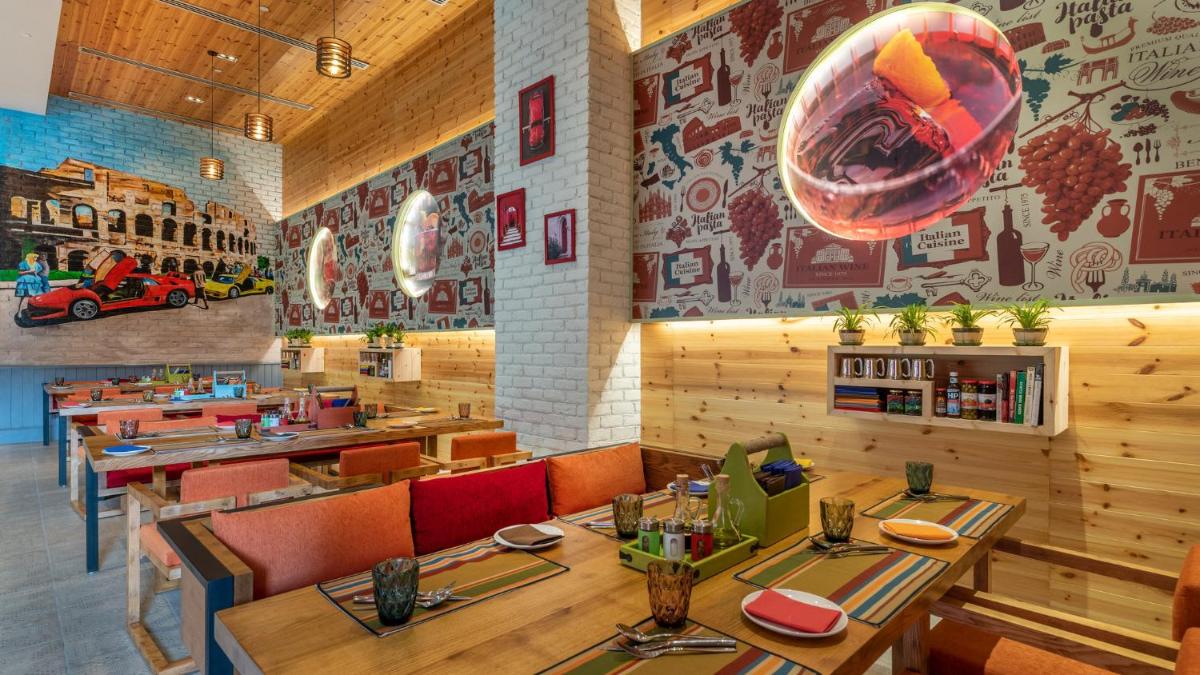 a restaurant with wooden tables and chairs and a mural at Holiday Inn New Delhi Aerocity by IHG in New Delhi