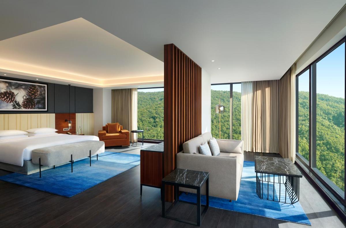 a bedroom with a bed and a living room at Hyatt Regency Dehradun Resort and Spa in Dehradun