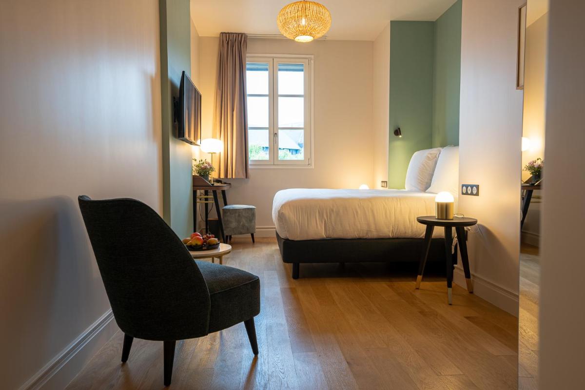 une chambre d'hôtel avec un lit, une chaise et une fenêtre dans l'établissement L'INVITATION AU VOYAGE - Hôtel & Spa, à Honfleur